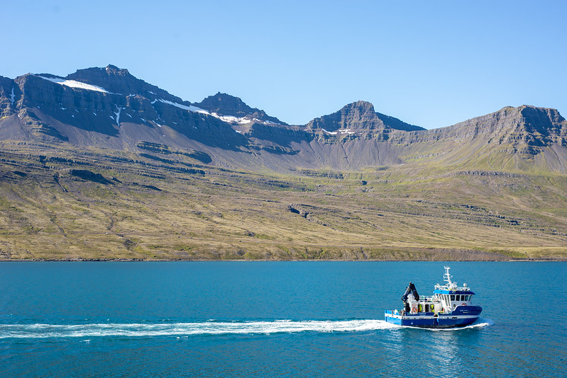 A small boat cruises through a fjord in eastern Iceland, 2022.